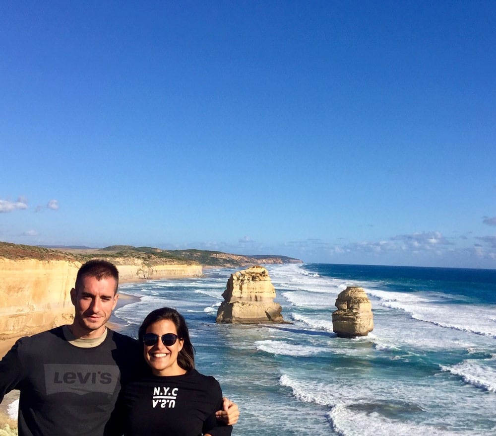 chico y chica posando a cámara y detrás los apóstoles de la ciudad de Melbourne